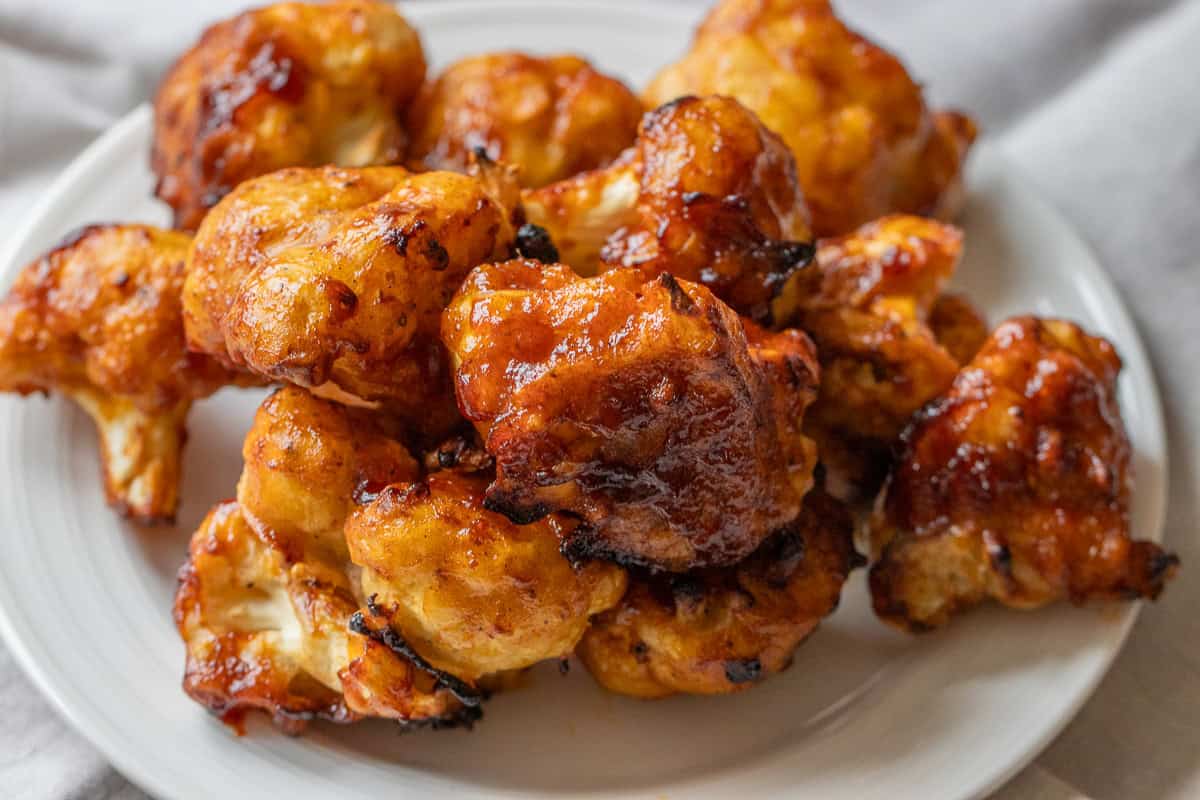 A plate of air fried cauliflower wings with sauce.