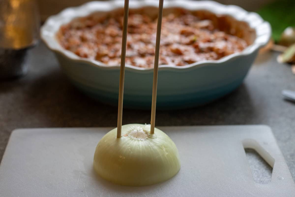 2 bamboo skewers are pushed into a half onion