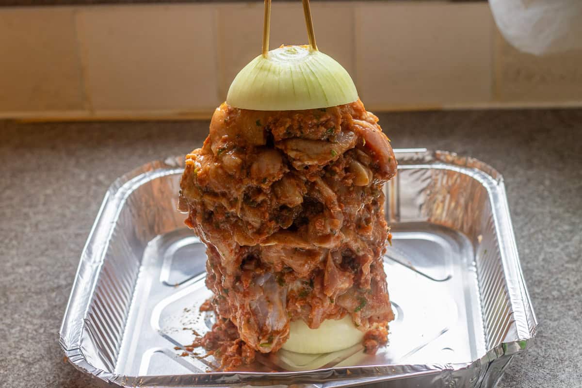 marinated chicken thighs are threaded into skewers, secured with half onion