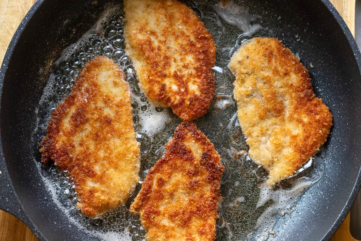 pan frying breaded chicken cutlets for making chicken parmesan sandwich