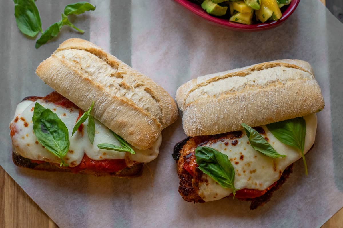 2 chicken parmesan sandwiches served with mango avocado salad on the side