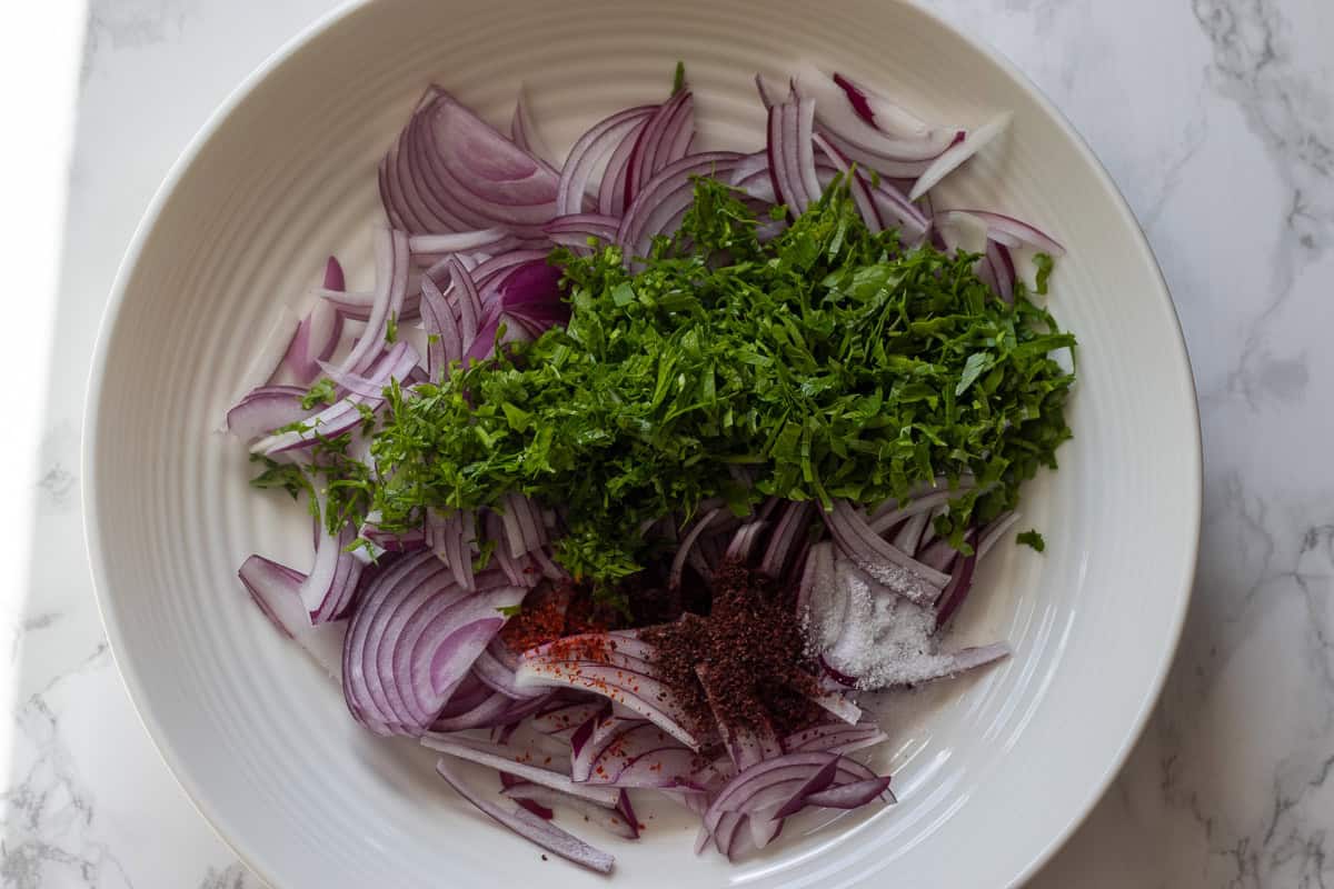 chopped parsley, sumac, chili, and salt are added to sliced red onions