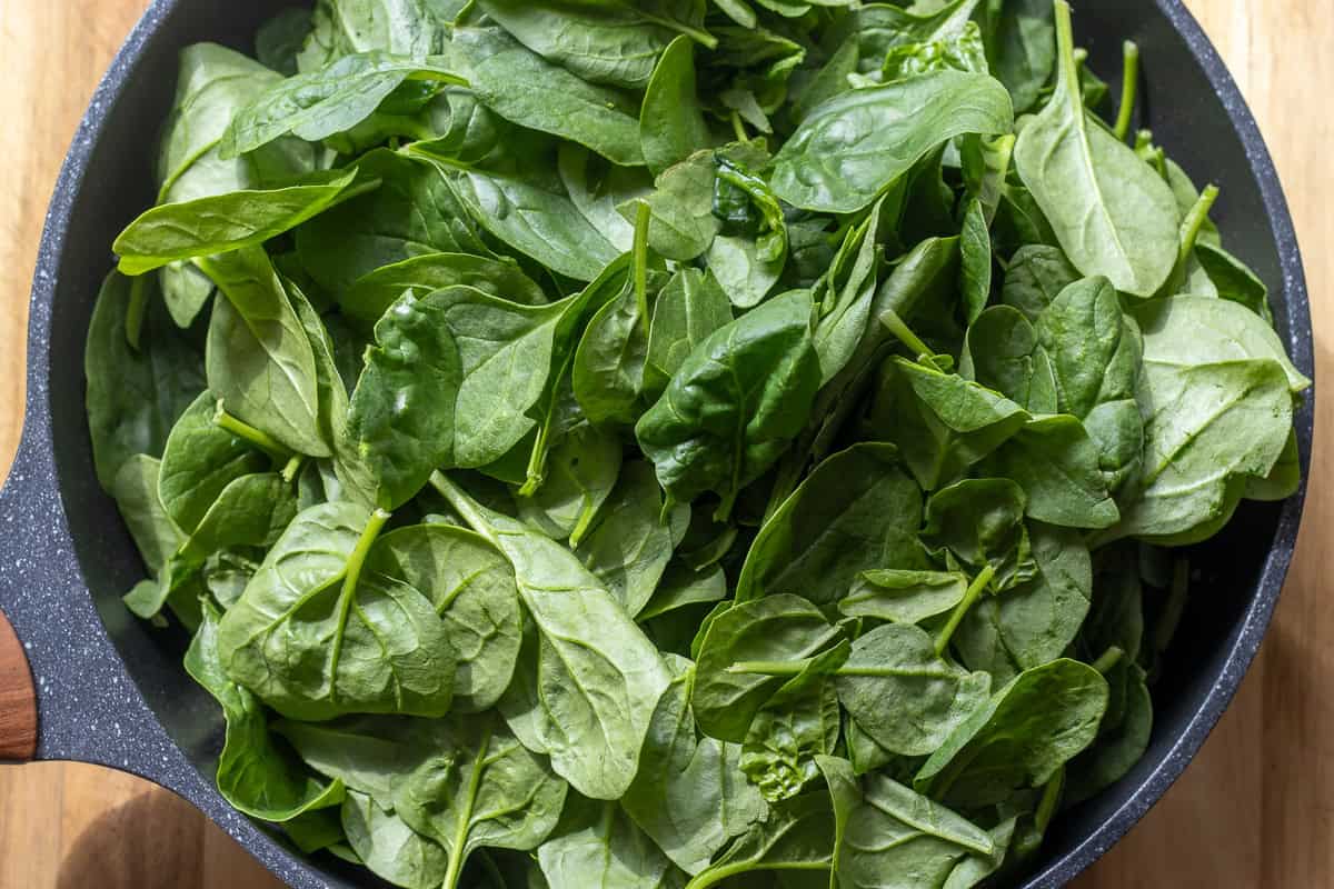 spinach leaves are added to sautéed shallots and garlic