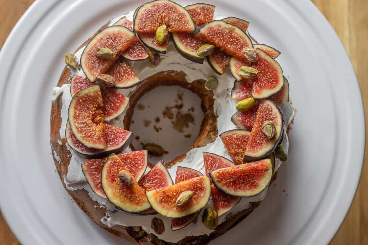 fresh fig cake made in a bundt and decorated with sliced fresh figs and pistachio