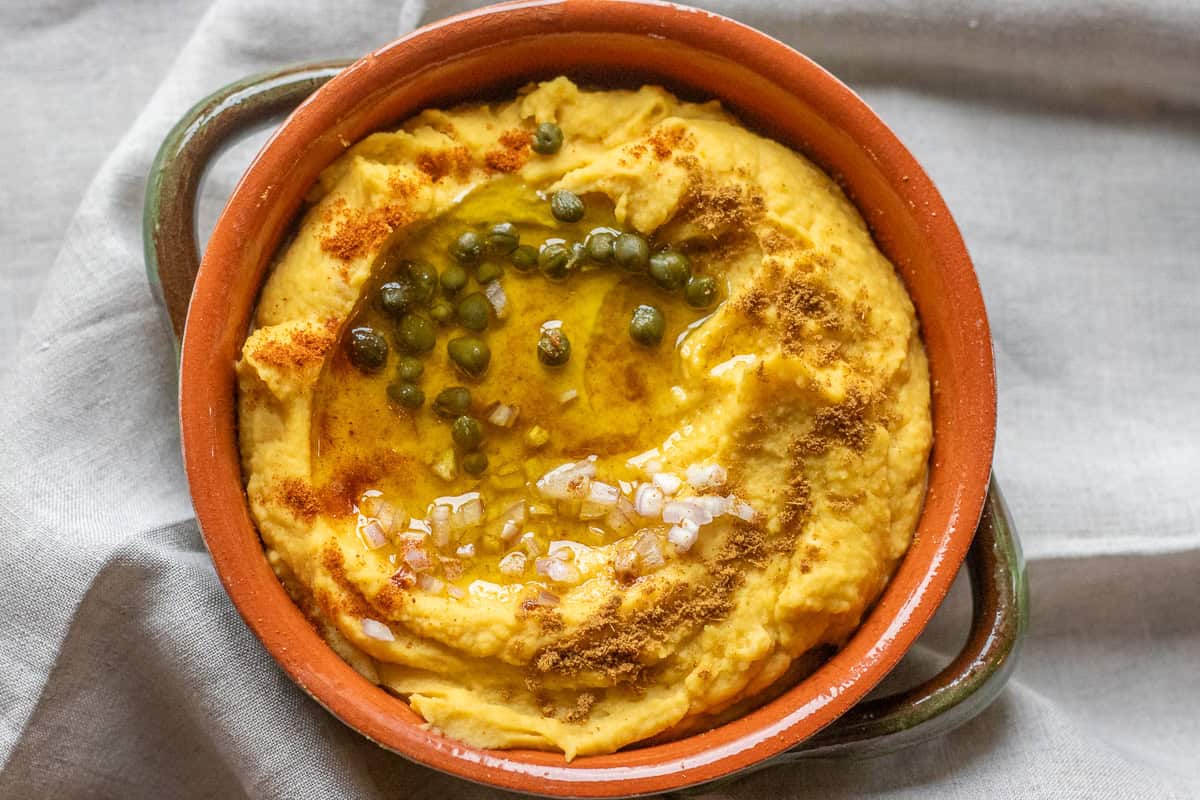 greek fava dip is garnished with capers, paprika, and olive oil