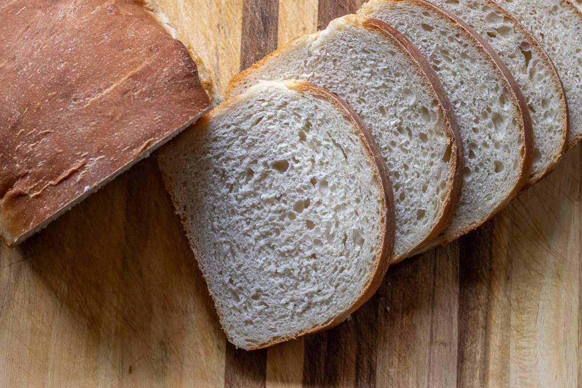 5 slices of sourdough bread on a wooden cutting board.