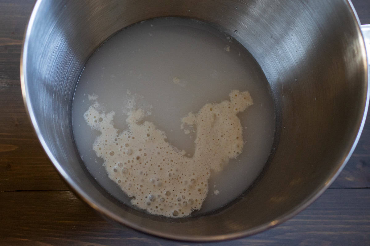 Active sourdough starter is mixed with water in a bowl.