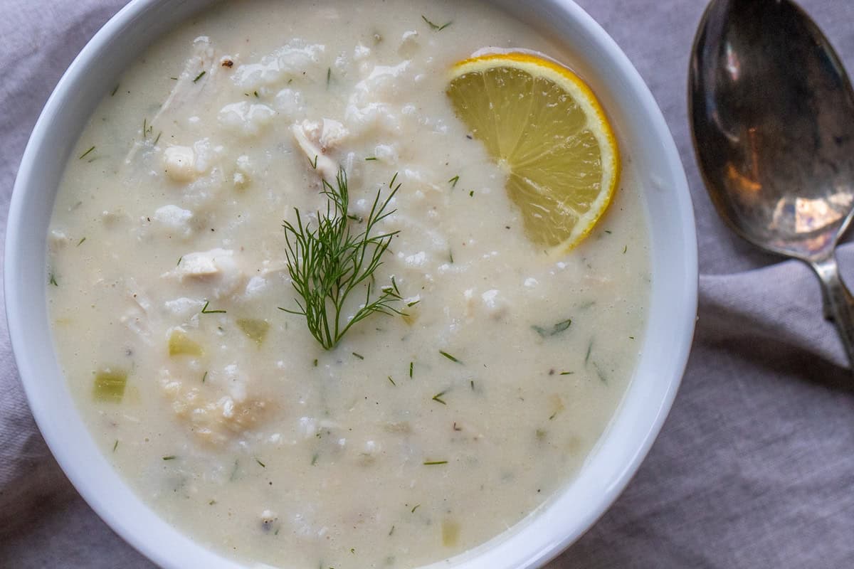 Greek lemon chicken soup garnished with fresh dill and lemon slices.