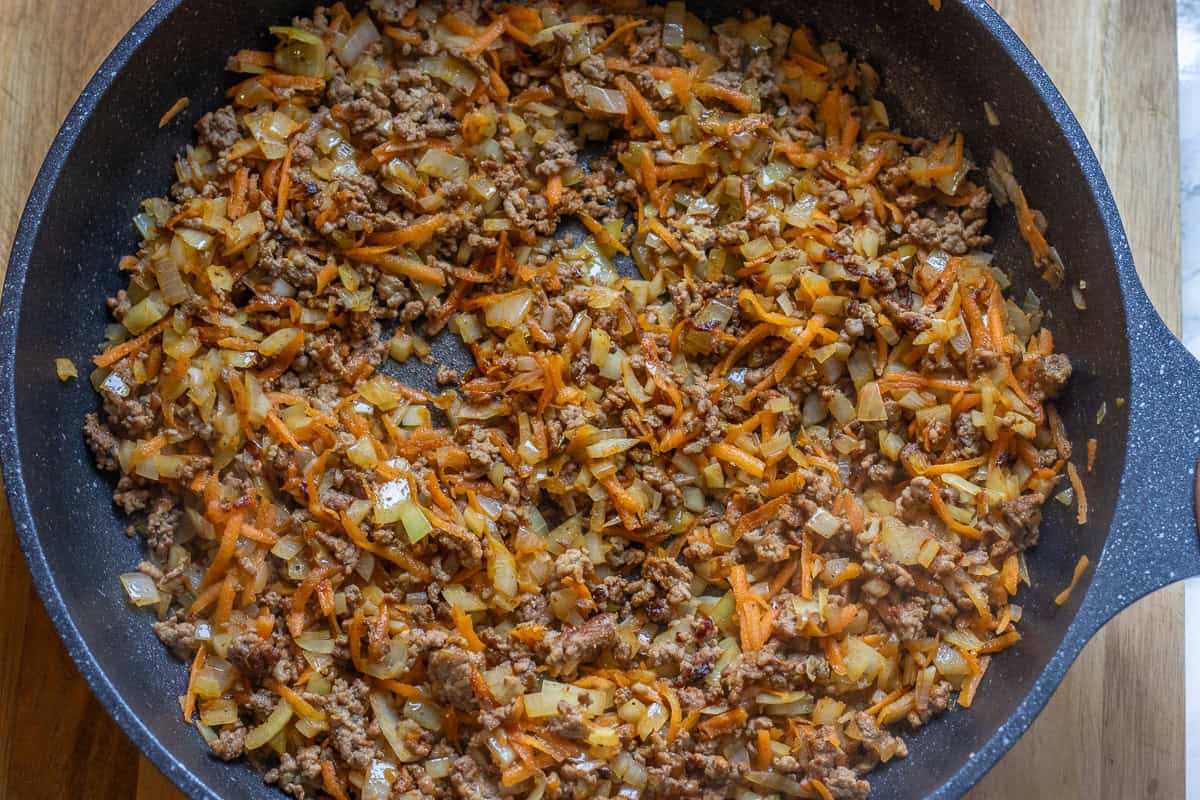 sautéing carrots and onions in a pan