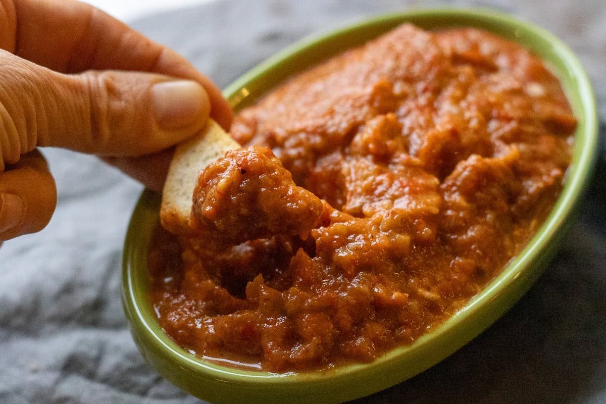 dipping ajvar with a piece of pita chip