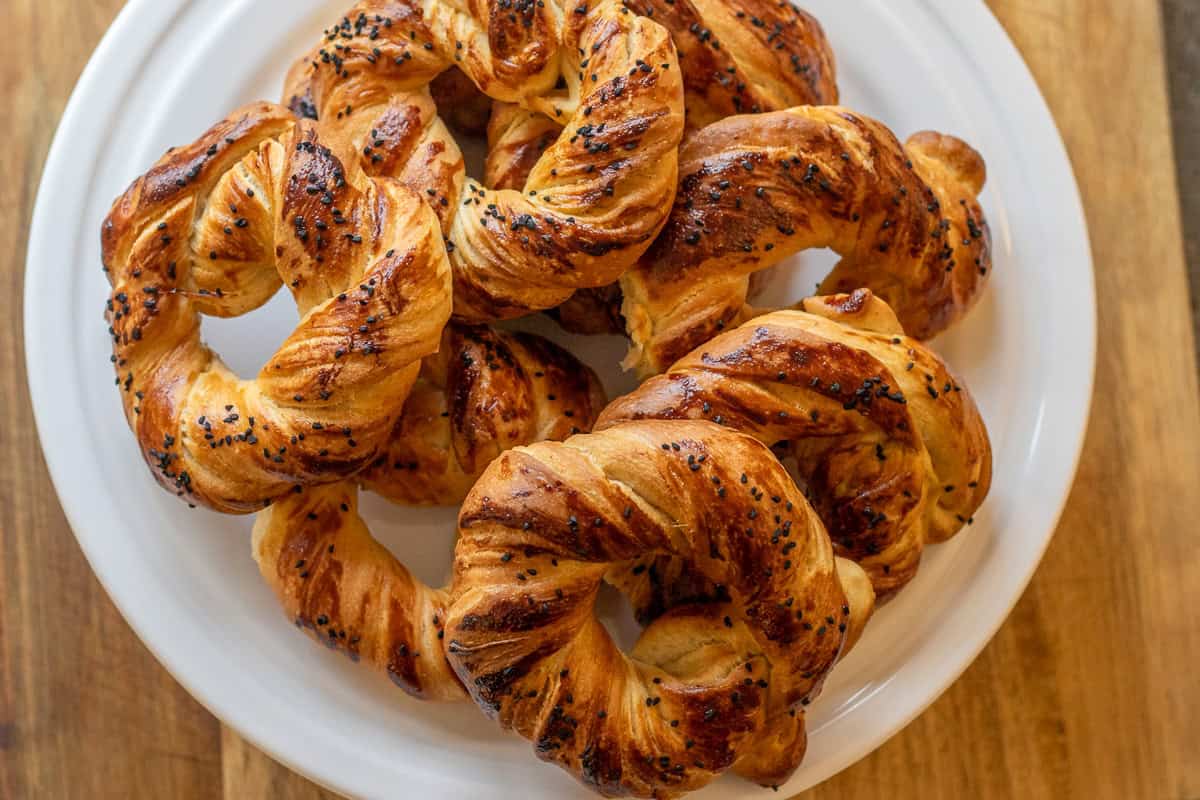 8 pieces of freshly baked acma - Turkish soft bread rings on a white plate
