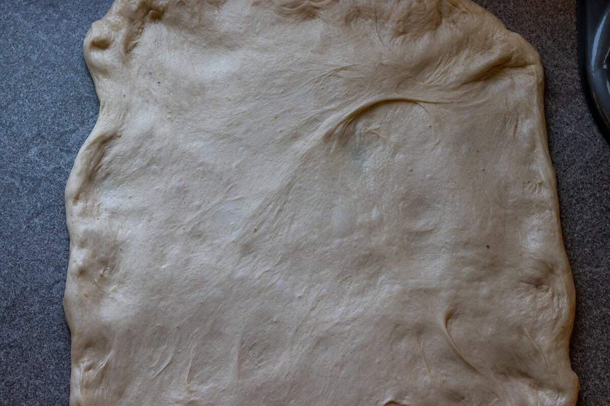 the dough ball is flattened on a lightly oiled worktop