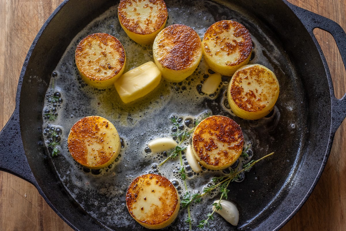 butter, thyme, and garlic are added to the skillet