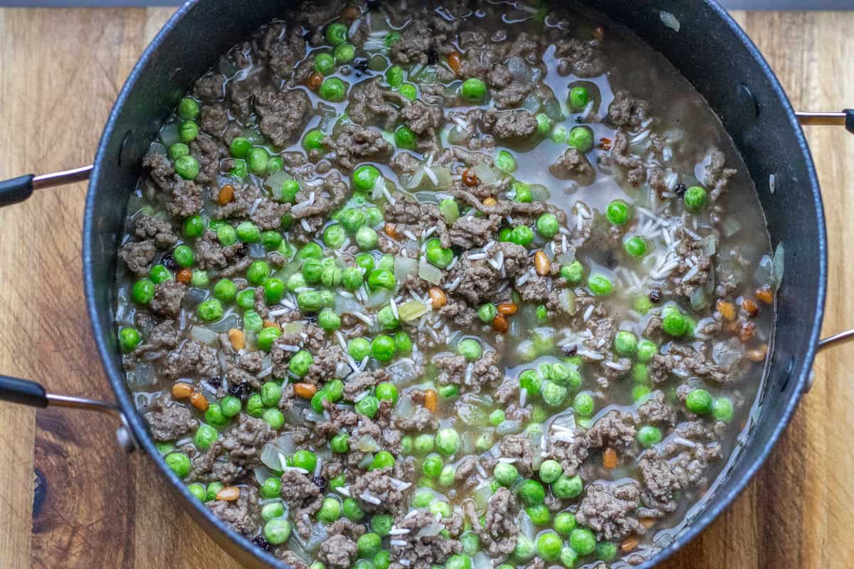 rice, peas, and stock are added to the pot