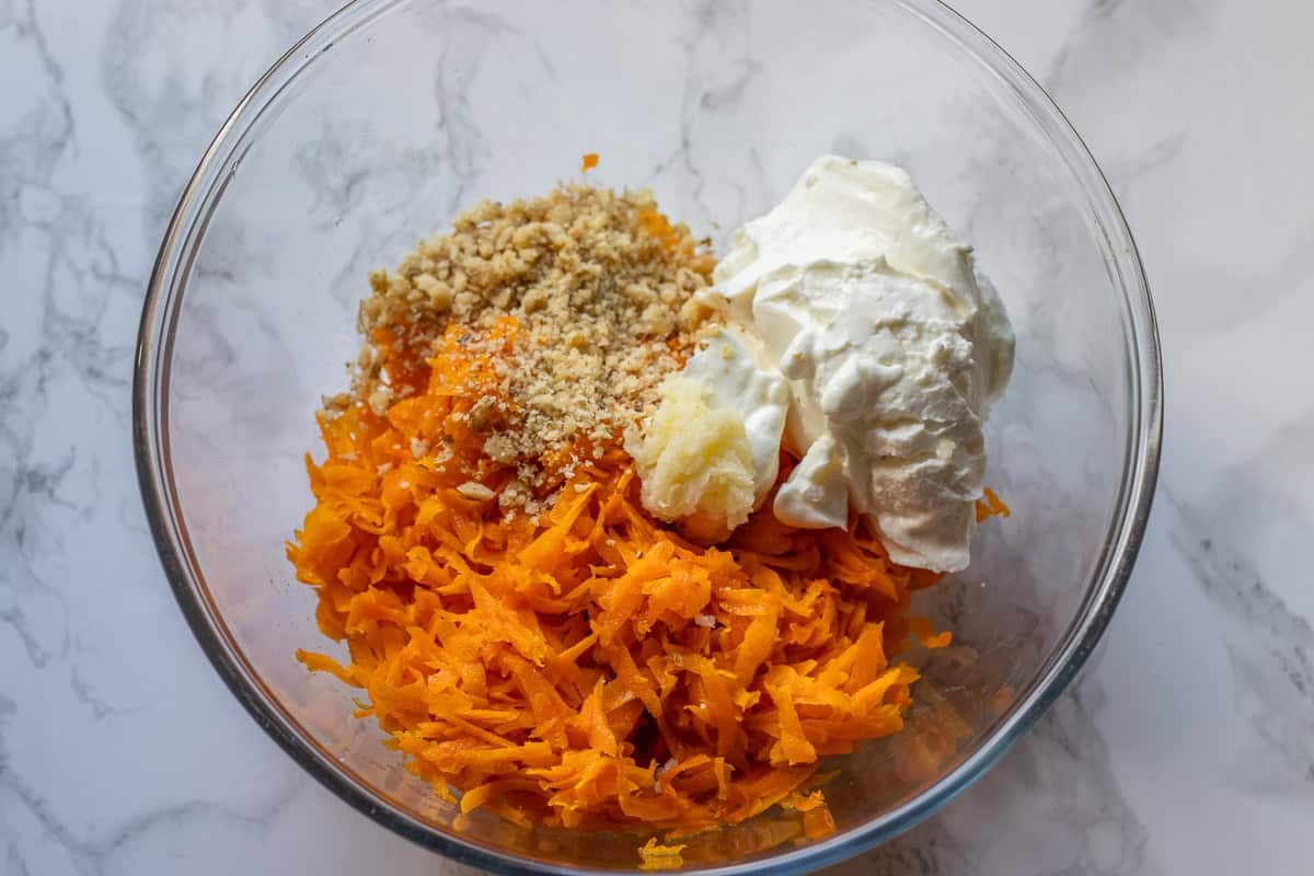 sautéed carrots, yogurt, crushed walnuts, and garlic are placed in a bowl