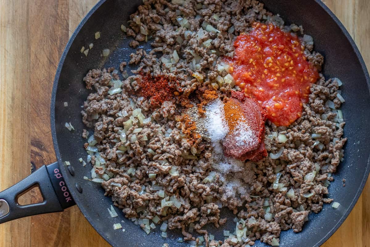 tomato paste, grated tomatoes, and seasoning are added to ground beef