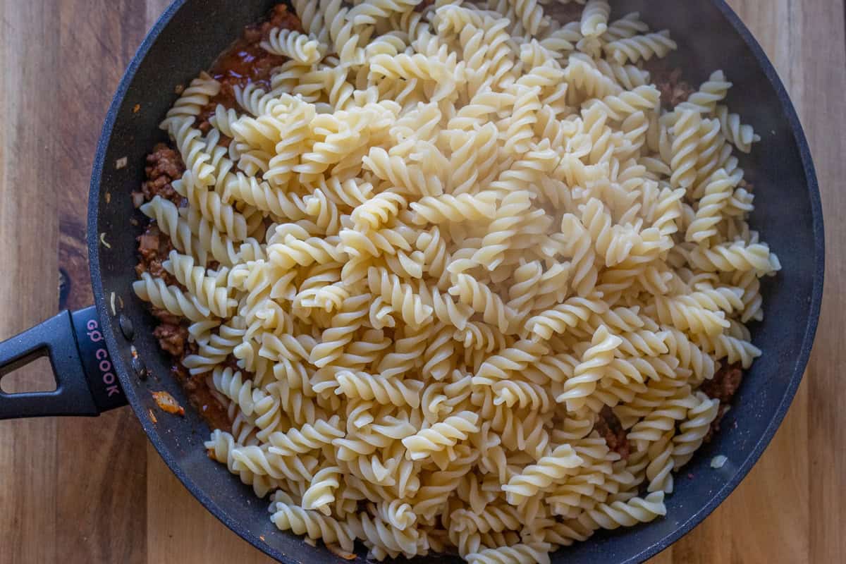 cooked pasta is added to ground beef sauce
