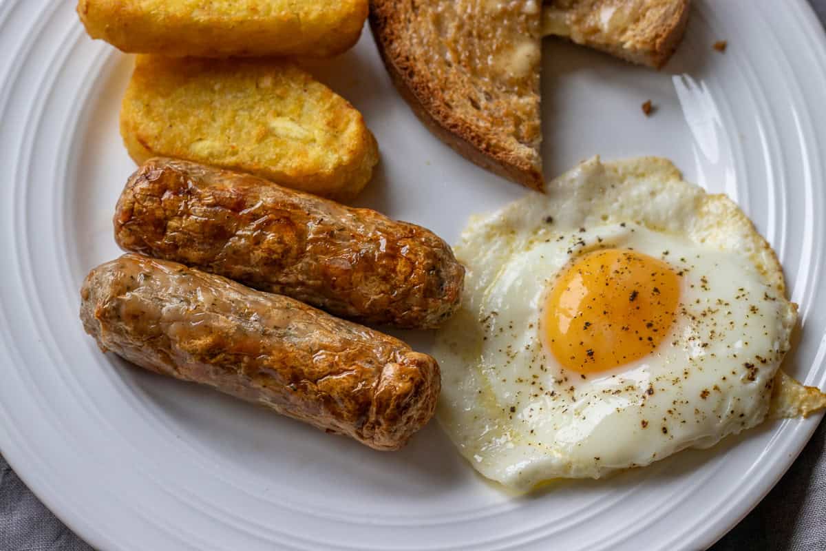 A plate with sausage, bread and eggs.