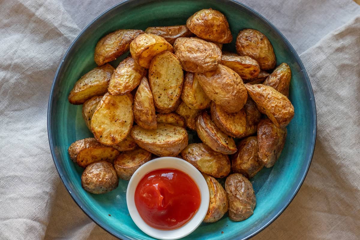 Baked potato with ketchup on a blue plate.
