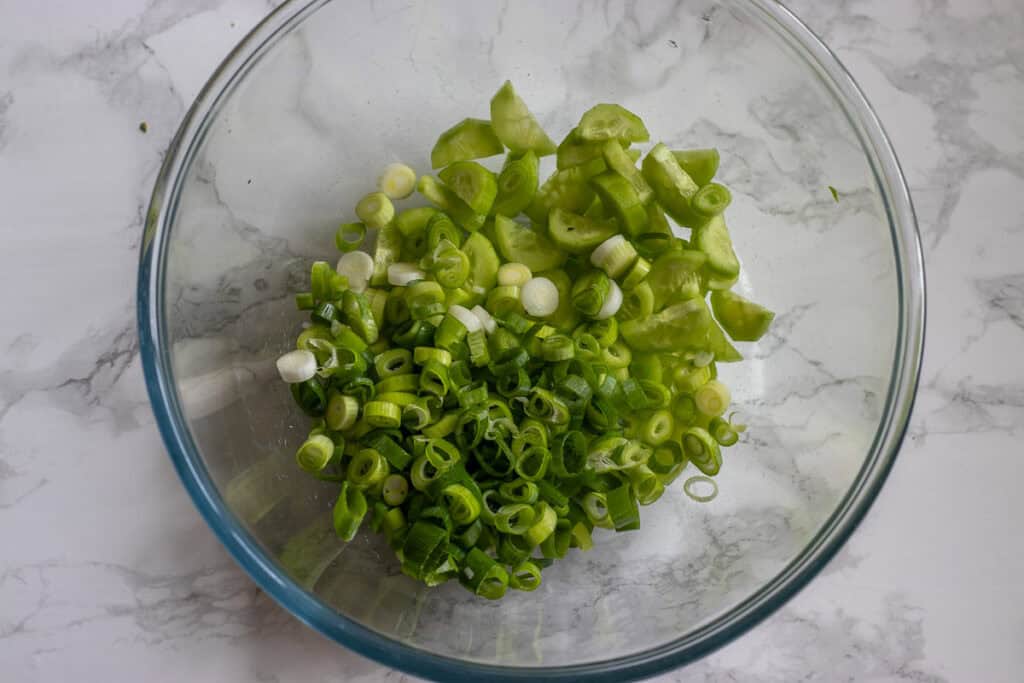 shredded lettuce is added to scallions and cucumbers