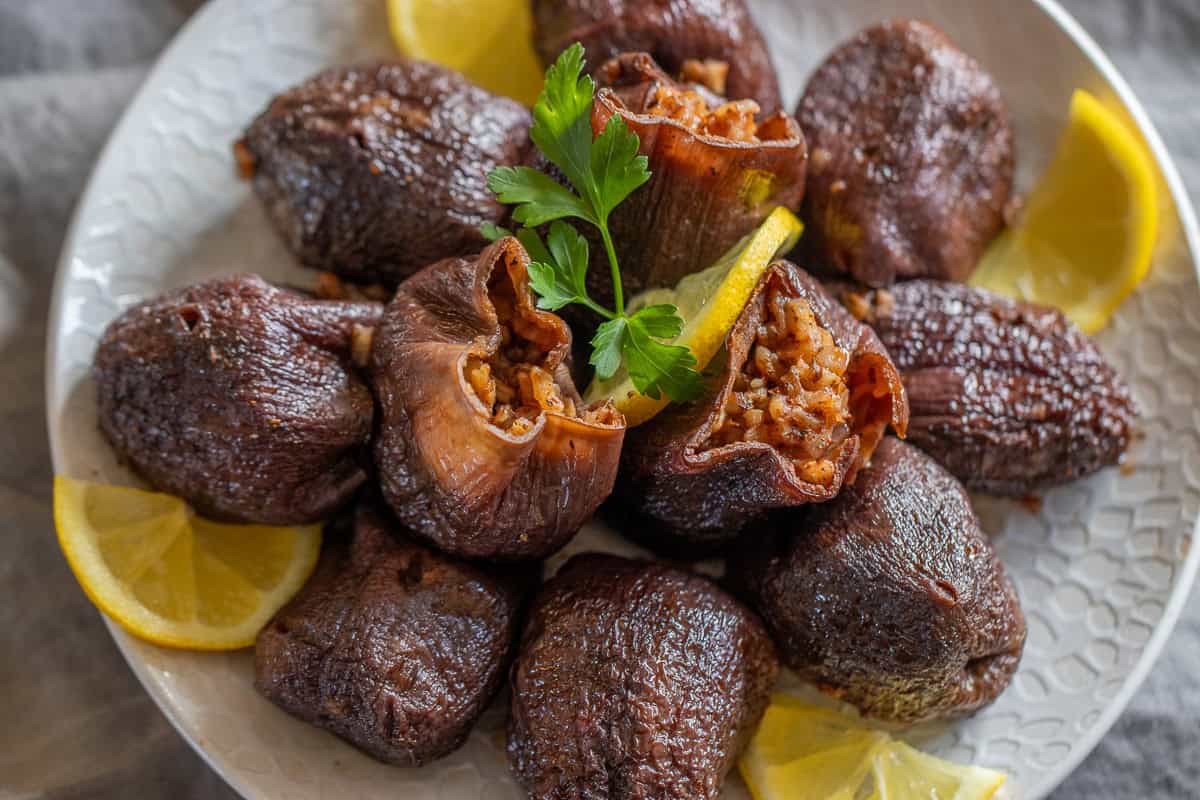 kuru patlıcan dolması garnished with lemon slices and parsley leaves