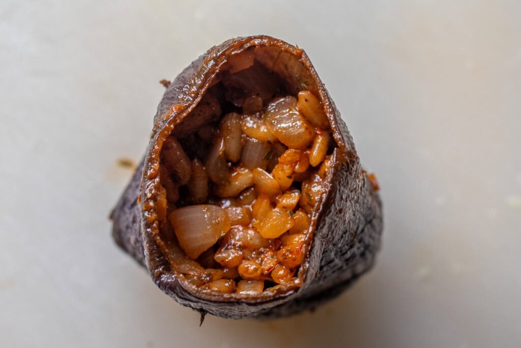 a piece of eggplant is filled with rice stuffing