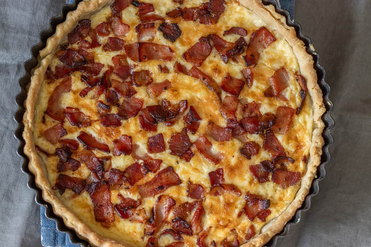 A quiche with bacon and cheese in a pan