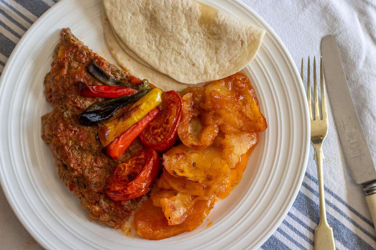 a portion of tepsi kebab is served with flatbread on the side