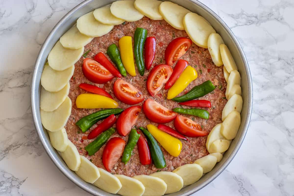 the meat is topped with thinly sliced potatoes and vegetables