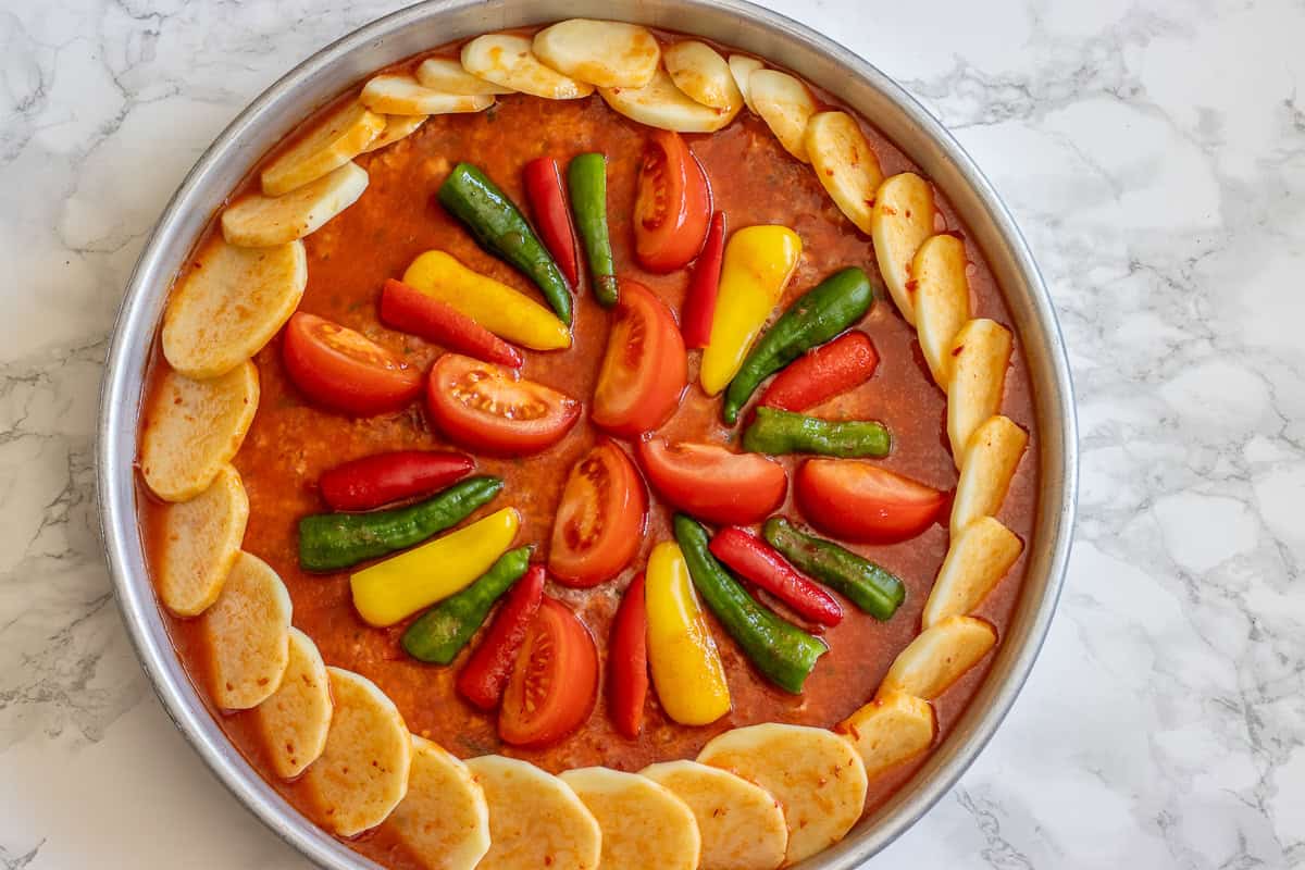 tomato sauce is poured over meat and potatoes