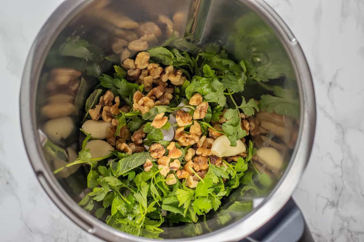 garlic, herbs, and walnuts are placed in a food processor