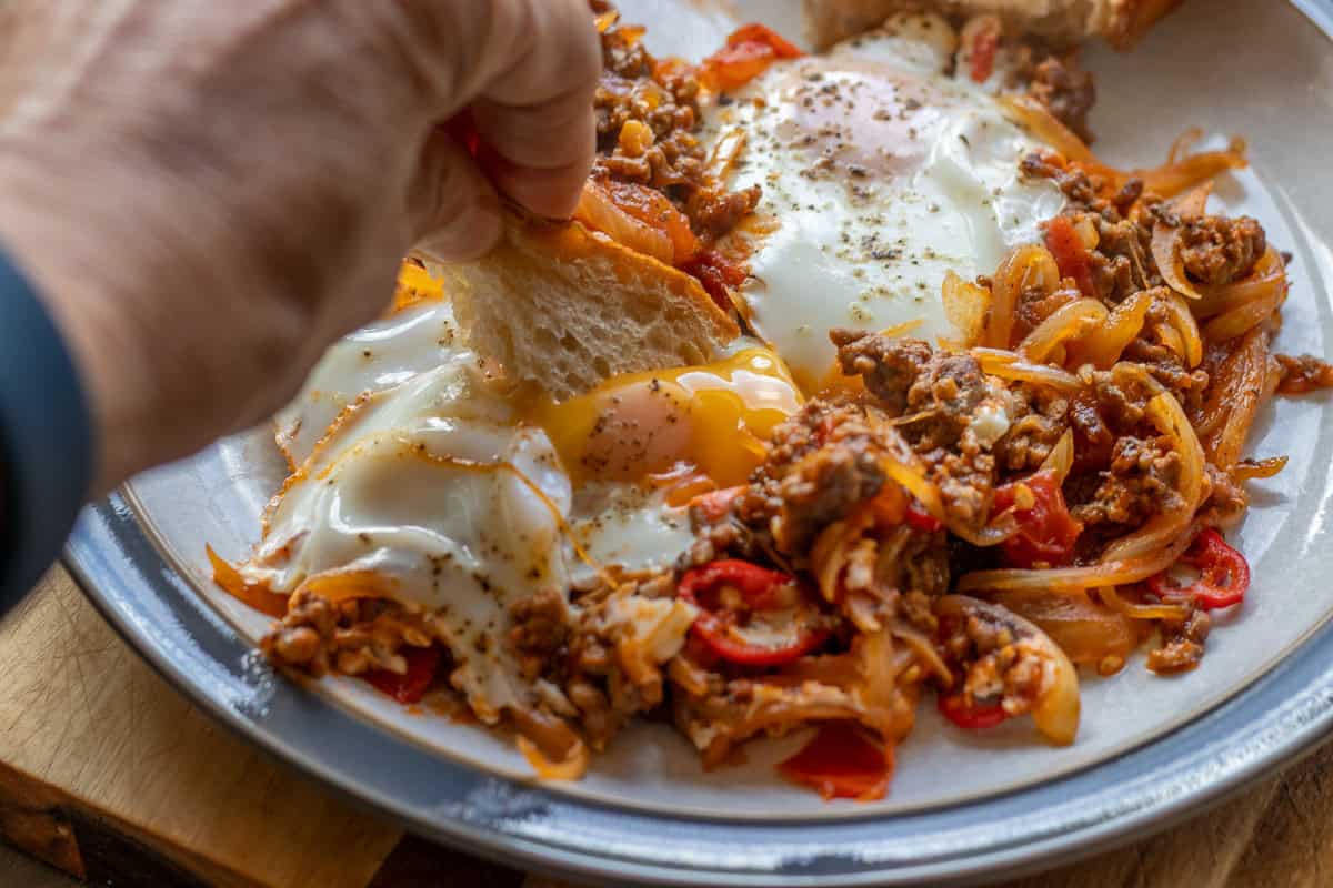dipping a piece of crusty bread into an egg