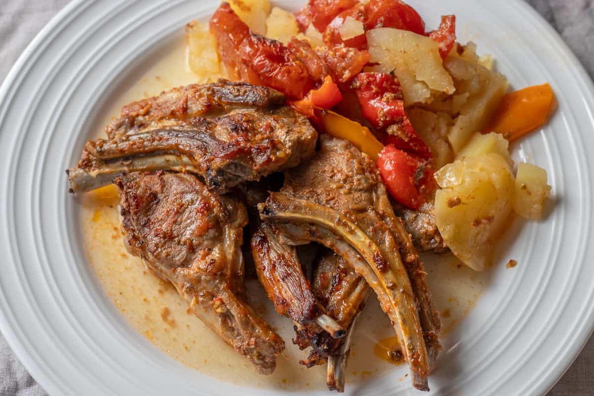 a plate of baked lamb chops and vegetables