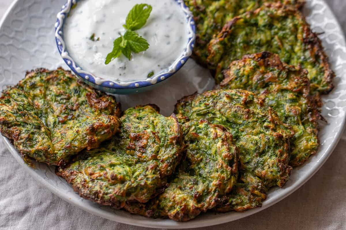 A plate of zucchini fritters with a dip.