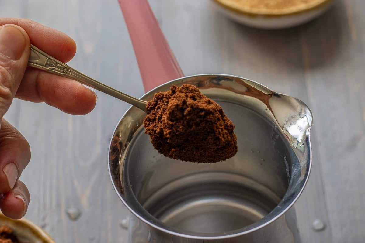 adding a heaping teaspoon of turkish coffee to cezve