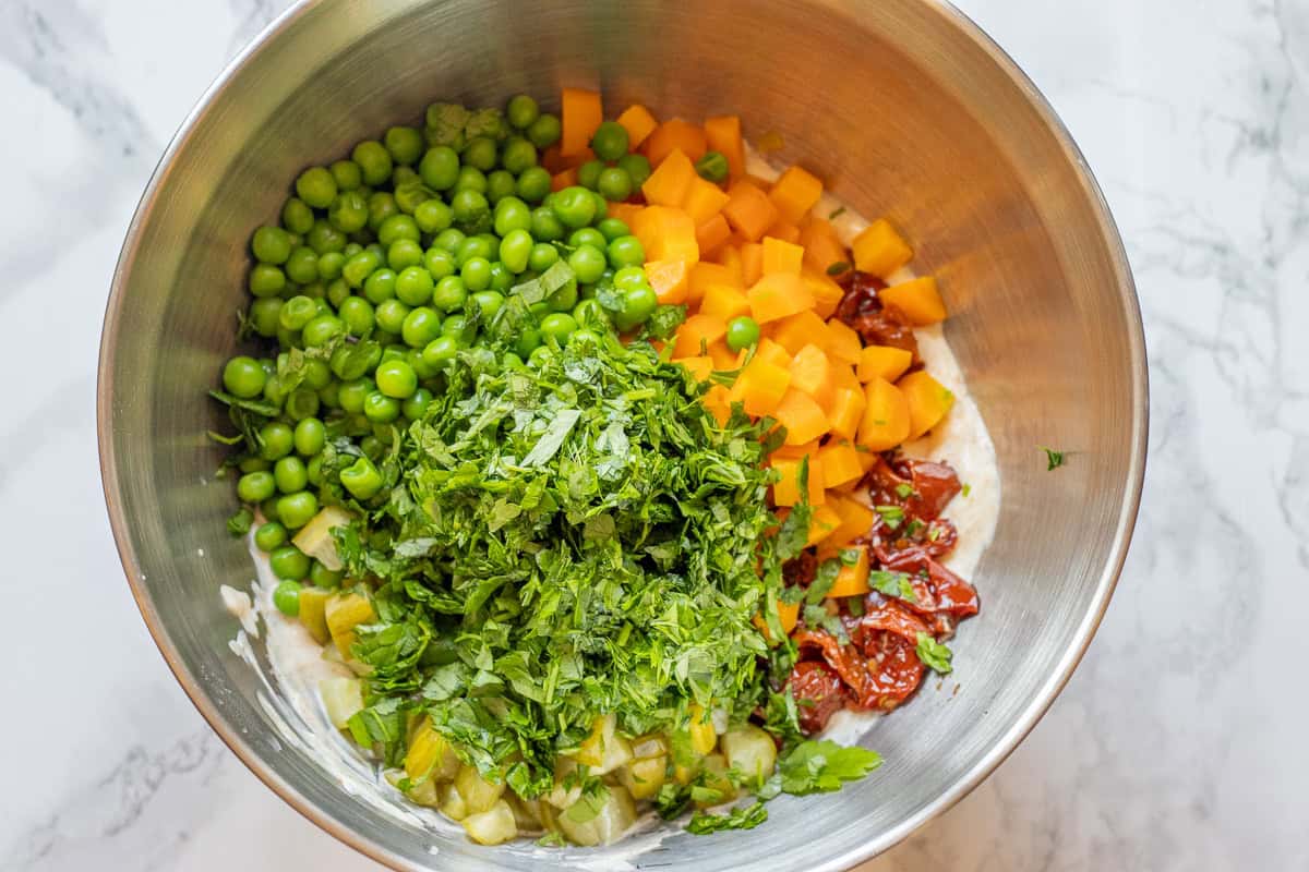 chopped vegetables and herbs are mixed with the sauce in a bowl