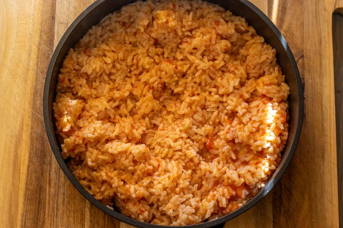 tomato rice is fluffed with a fork after cooking