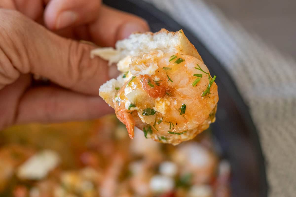 holding a piece of shrimp with bread