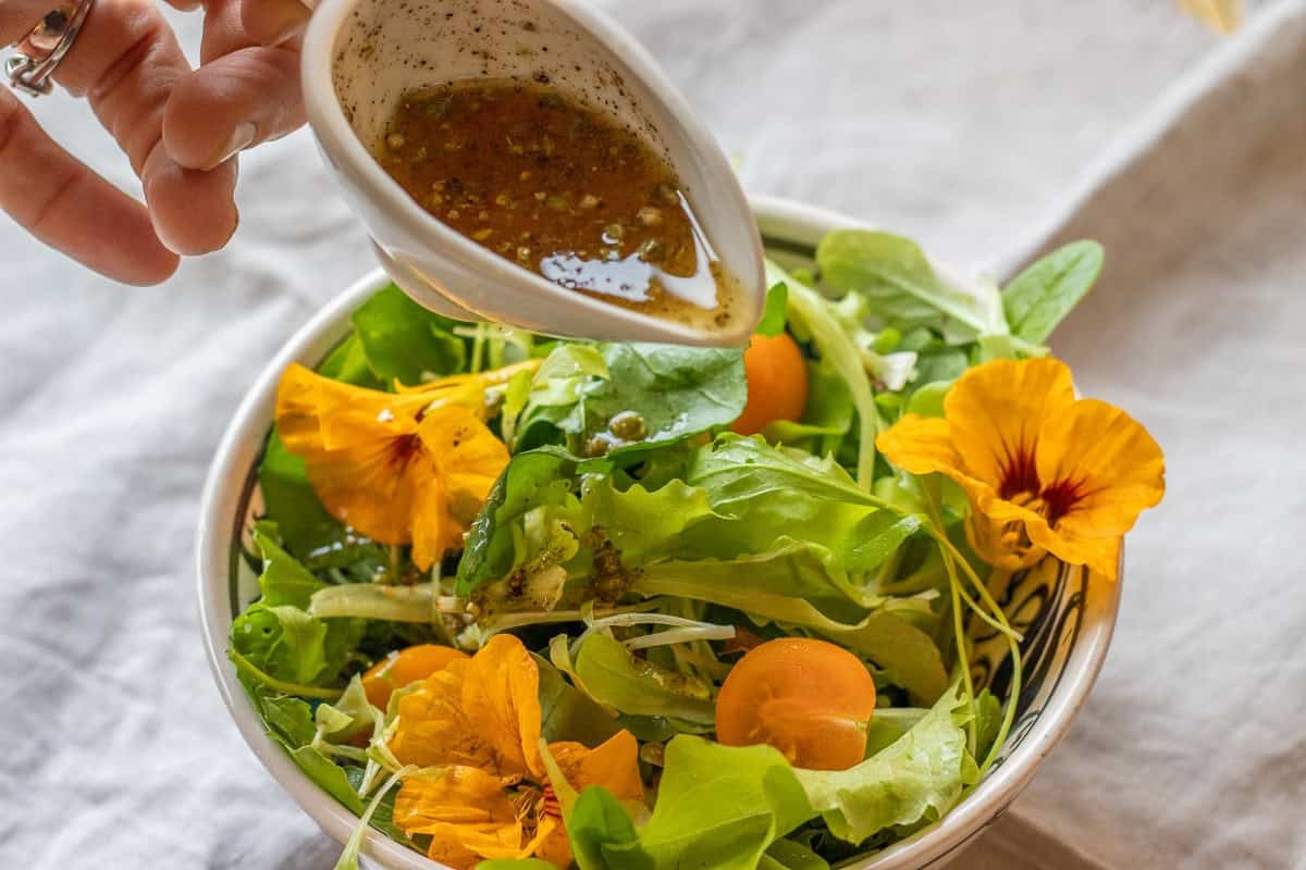 pouring mediterranean salad dressing over salad