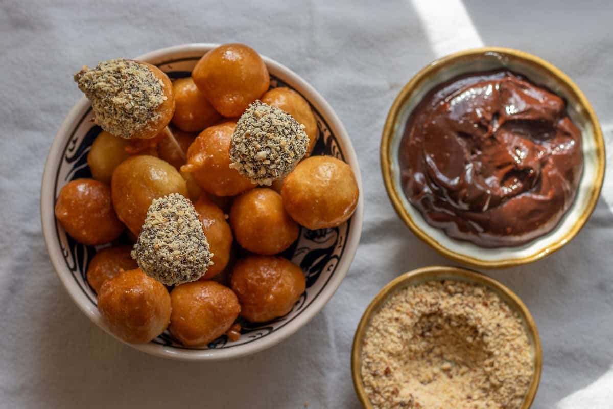 lokma dessert dipped in choclate and sprinkled with nuts