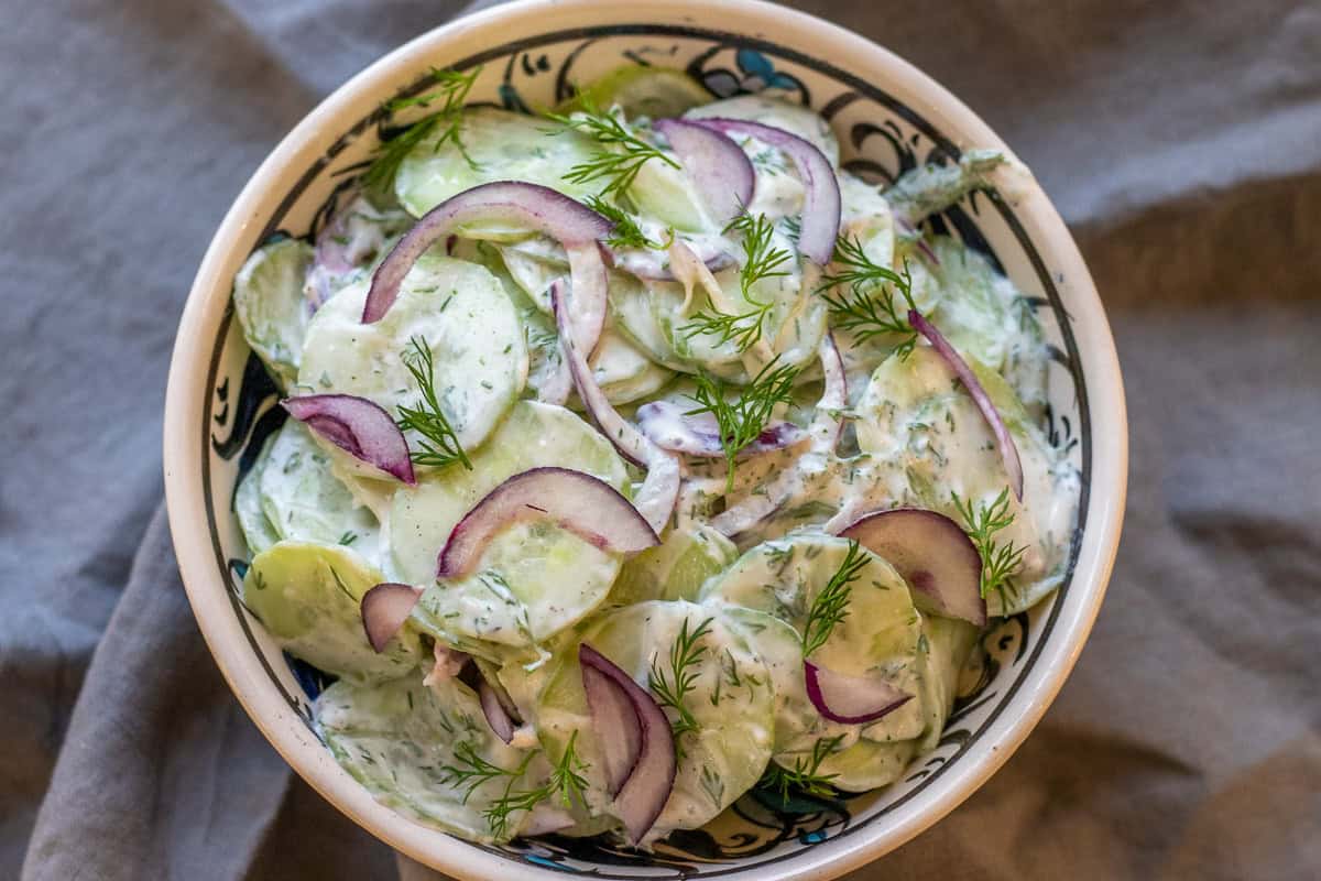 a bowl of creamy cucumber dill red onion salad