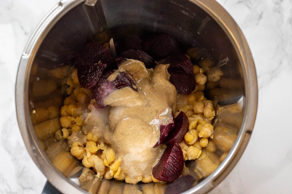 ingredients for beet hummus recipe are placed in a bowl of food processor
