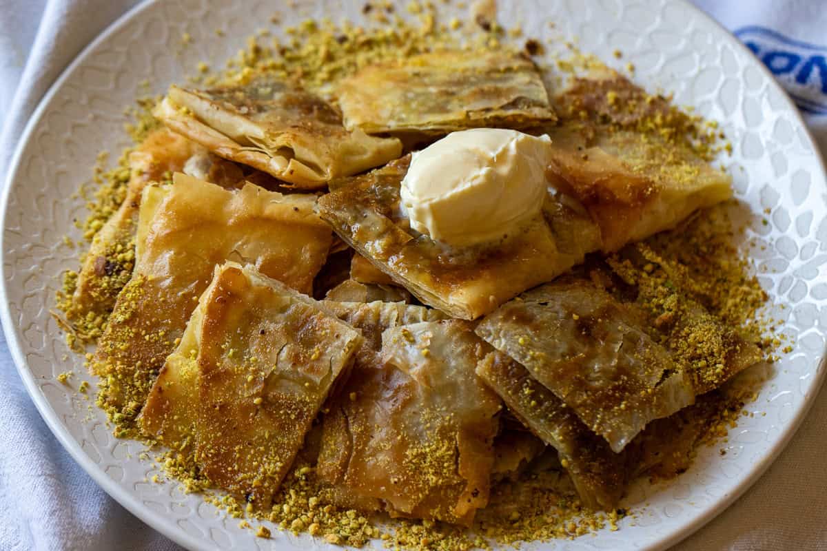 Katmer dessert is cut into squares and served with clotted cream.